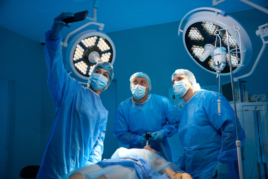 Doctor taking selfie on smartphone with surgeons after successful operation