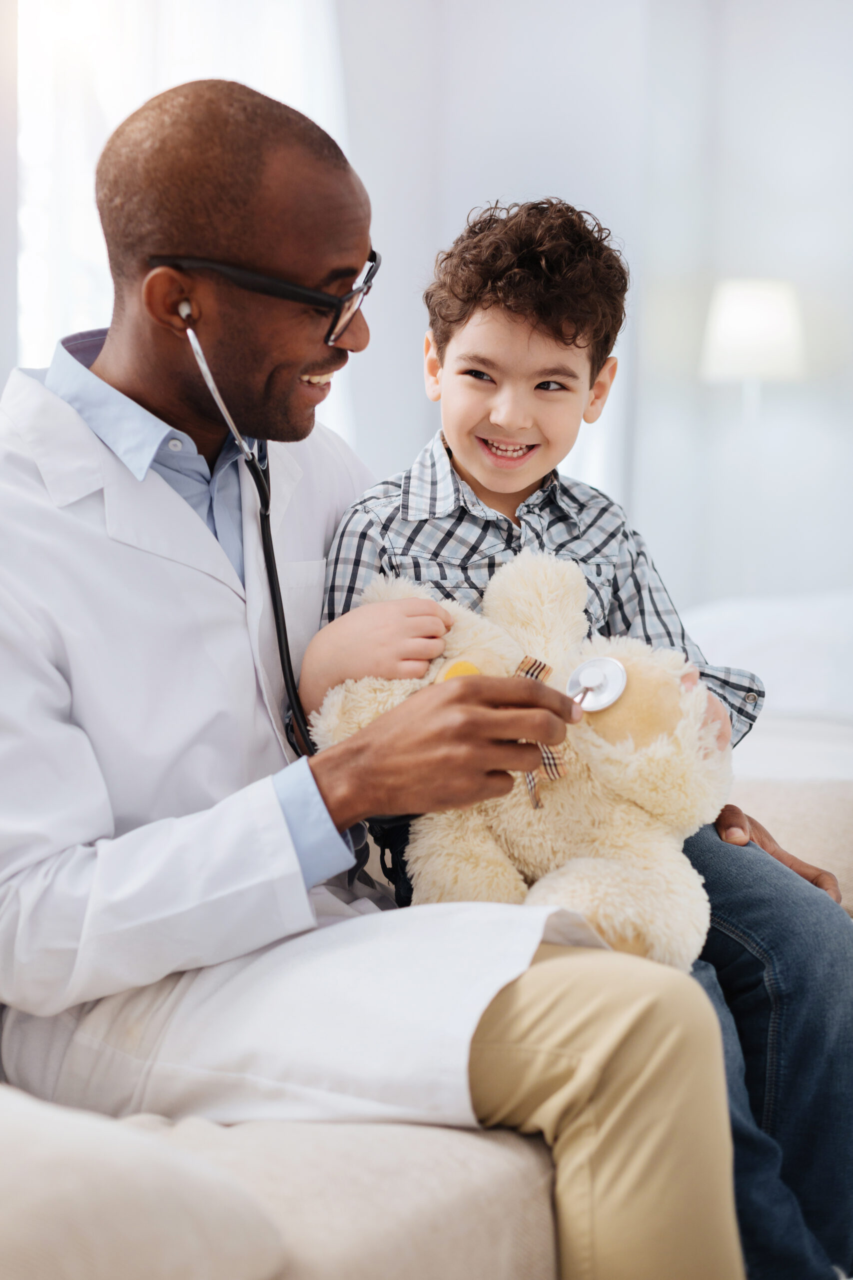 Jovial male doctor helping plush bear