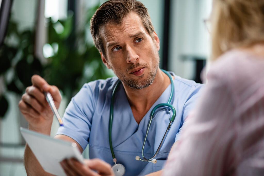 General practitioner using digital tablet while having consultation with his patient.